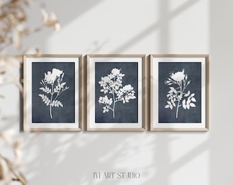 May include: A set of three framed wall art prints featuring white botanical rose silhouettes against a dark navy blue textured background. Each print is encased in a light wood frame. The text IYI ART STUDIO is printed at the bottom center.
