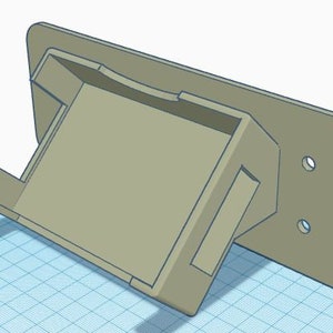 May include: A beige plastic wall mount with a rectangular opening. The mount has two small holes on the side.