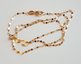 May include: A gold chain necklace with a delicate, twisted design. The chain is made up of small, oval-shaped links.