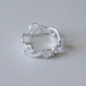Puede incluir: Un anillo de plata con un delicado dise&ntilde;o de espiral. El anillo est&aacute; hecho de un metal liso y pulido y tiene un aspecto simple y elegante.