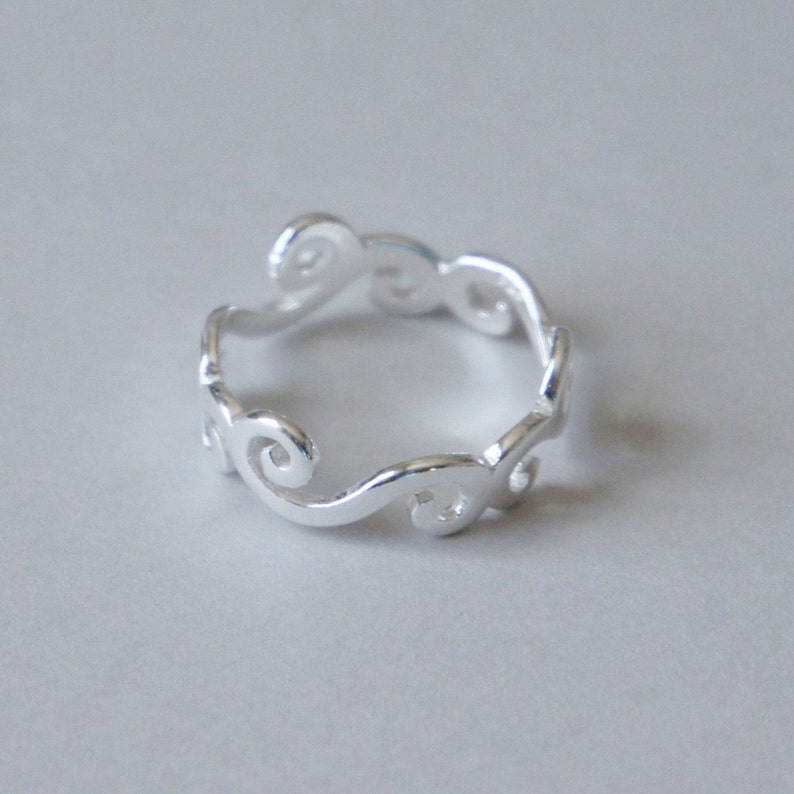 Puede incluir: Un anillo de plata con un delicado dise&ntilde;o de espiral. El anillo est&aacute; hecho de un metal liso y pulido y tiene un aspecto simple y elegante.
