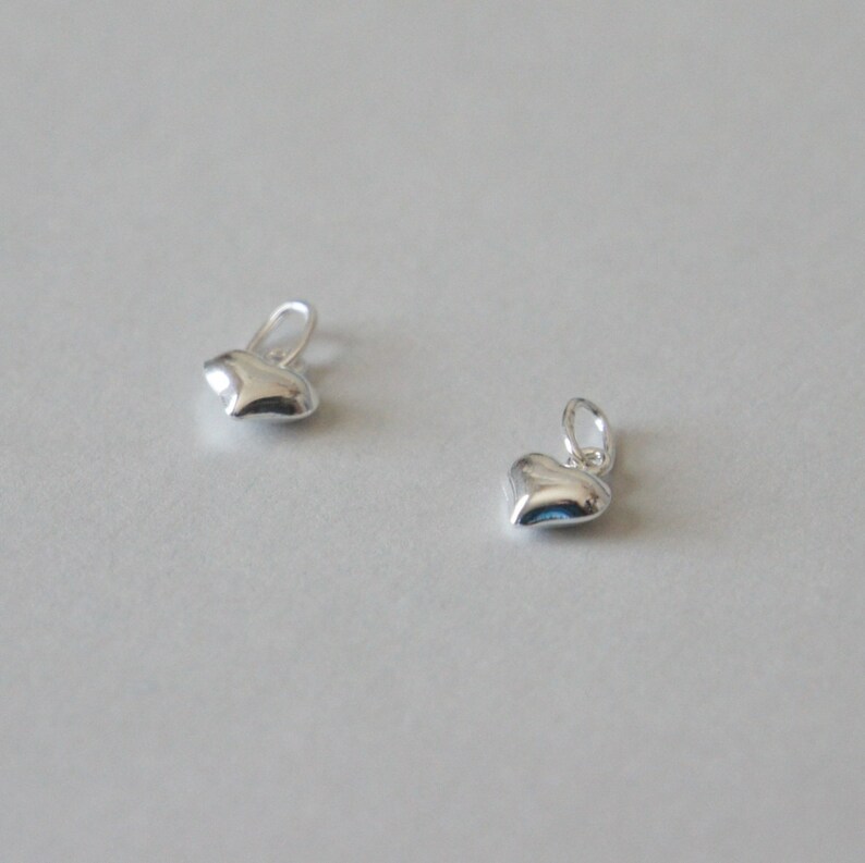 May include: Two silver heart-shaped charms with a loop at the top for attaching to jewelry.