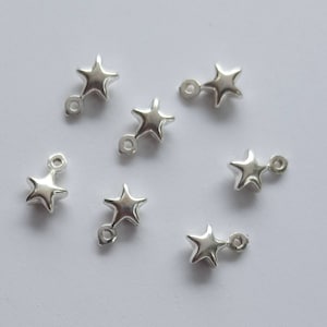 May include: Silver star-shaped charms with jump rings. The charms are ideal for adding a touch of sparkle to jewellery projects.