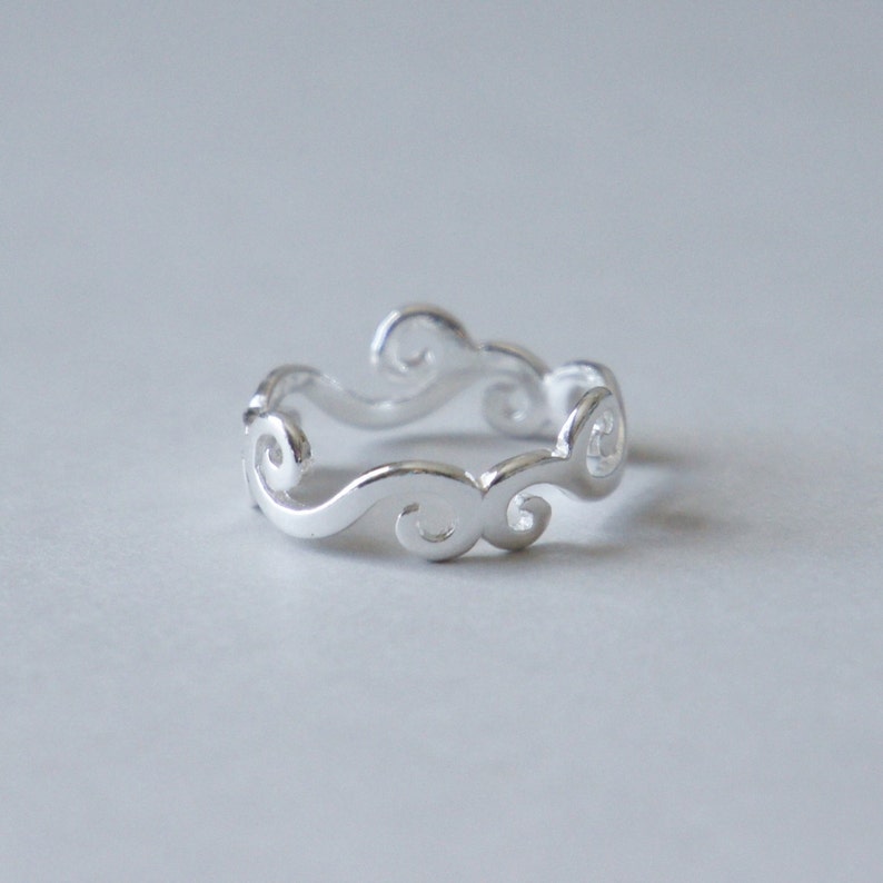Puede incluir: Un anillo de plata con un delicado dise&ntilde;o de espiral. El anillo est&aacute; hecho de un metal liso y pulido y tiene un estilo simple y elegante.