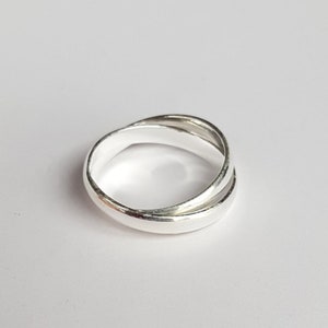 May include: A silver ring with a unique intertwined design. The ring is smooth and polished, with a simple and elegant style.