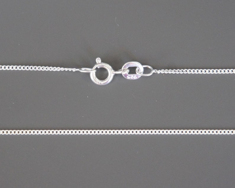 May include: A silver chain necklace with a lobster clasp. The clasp is marked with "925", indicating that the necklace is made of sterling silver.