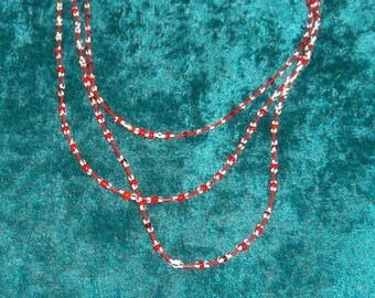 May include: A three-strand necklace with red and white beads. Matching earrings with red beads are included.