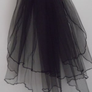 May include: A black tulle veil with a scalloped edge. The veil is layered and has a soft, flowing texture.