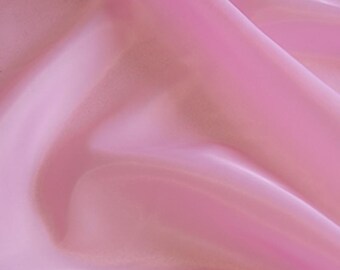 May include: A piece of light pink fabric with a smooth, semi-sheer texture. The material is draped in soft, flowing folds that create subtle highlights and shadows across the surface, emphasizing the delicate and lightweight nature of the textile.