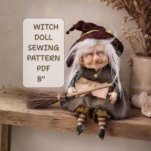 Op de afbeelding: Een heksenpop met lang wit haar, gekleed in een donkerbruine puntmuts en een bijpassende jurk met een lichtgekleurd schort. De pop heeft gestreepte leggings, zwarte schoenen en houdt een bezempje vast. Tekst: WITCH DOLL SEWING PATTERN PDF 8".