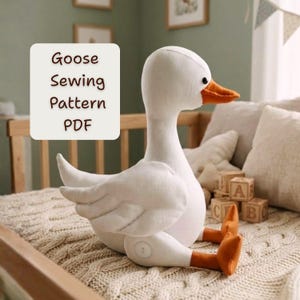 May include: A plush white goose with an orange beak and feet sits on a knitted blanket. The goose has a long neck and a round body. Text on a white square reads "Goose Sewing Pattern PDF".