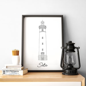 May include: A black and white line drawing of a lighthouse with the word "Sete" printed below it. The drawing is framed and hanging on a wall above a wooden shelf.