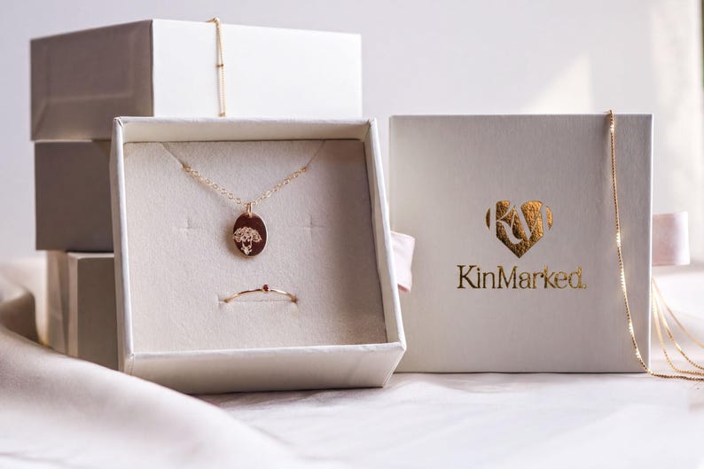 a jewelry box with a necklace and a pendant, as well as a box with the brand name "KinMarked" printed on it.