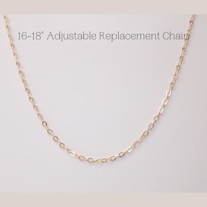 May include: A delicate gold-colored necklace chain. The text "16-18" Adjustable Replacement Chain" is displayed above the necklace. The chain is made of small, evenly spaced links and is designed to be adjustable.