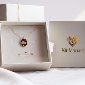a jewelry box with a necklace and a pendant, as well as a box with the brand name "KinMarked" printed on it.