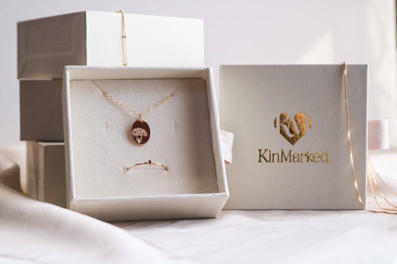 a jewelry box with a necklace and a pendant, as well as a box with the brand name "KinMarked" printed on it.