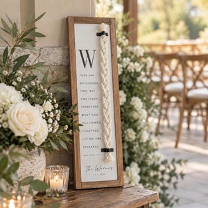 May include: A rectangular wooden sign with a white background featuring the letter W, the text They are no longer two, but one flesh, therefore what God has joined together, let no one separate, Matthew 19:6, The Warners, 11.7.2024, and a braided rope.
