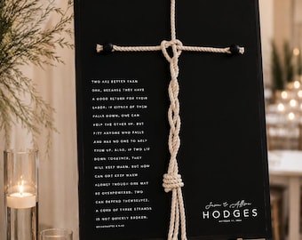 May include: Black sign with white text and a rope cross design. The sign includes the text "Two are better than one..." and the names "Jason & Allison Hodges". The sign is displayed on a gold easel.