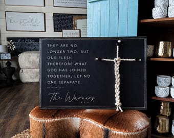 May include: Black chalkboard sign with white text that reads "They are no longer two, but one flesh. Therefore what God has joined together, let no one separate. The Warners 8:25". A white rope tied in a knot is attached to the sign with a small black cross.