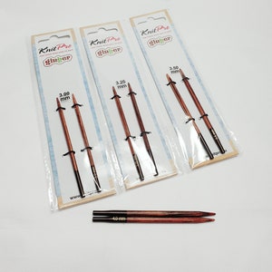 Op de afbeelding: Drie pakketten Knit Pro Ginger breinaalden in de maten 3,00 mm, 3,25 mm en 3,50 mm. De naalden zijn gemaakt van hout en hebben een donkerbruine kleur. De pakketten zijn gelabeld met het Knit Pro Ginger logo en de maat van de naalden.
