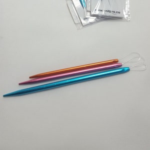 May include: Three sets of knitting needles in blue, pink, and orange. The needles are packaged in plastic and labeled "Knit Pro" with the text "Wool Needles".