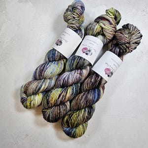 May include: Three skeins of yarn in a colorful, variegated pattern of blues, greens, yellows, and browns. The yarn is wrapped around white labels with the text "The Yarn Harlot" printed on them.
