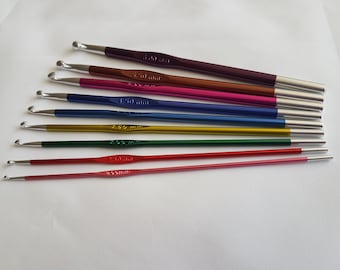 Puede incluir: Un juego de diez agujas de tejer de colores con puntas plateadas. Las agujas están ordenadas por tamaño, con la aguja más pequeña en la parte superior y la aguja más grande en la parte inferior. Las agujas están etiquetadas con su tamaño en milímetros.