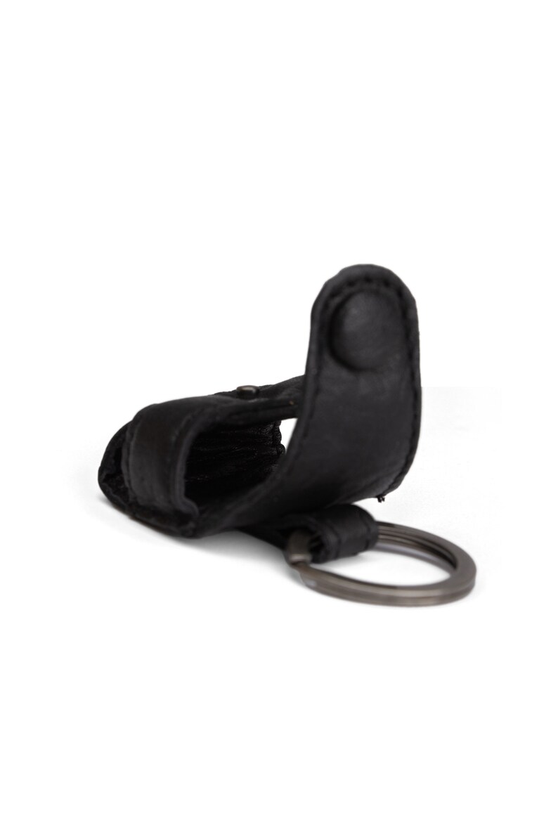 May include: Black leather key chain with a metal ring. The key chain has a loop for attaching keys.