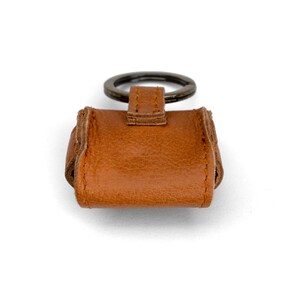 May include: A brown leather keychain with a metal ring. The keychain is designed to hold a small key or other item.