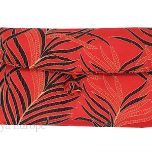 K&ouml;nnte beinhalten: Rote Clutch mit einem schwarzen und goldenen Palmenblatt-Muster. Die Clutch hat einen Klappverschluss mit einem Knopf.