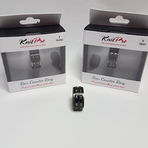 Puede incluir: Dos cajas negras con texto blanco que dice "Knit Pro" y "Row Counter Ring (A great jewellery piece too)". Las cajas contienen anillos de metal negro con números blancos. Los anillos tienen un diámetro de 18,2 mm y 19 mm.
