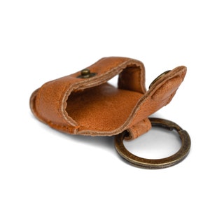 May include: A brown leather key chain with a small pocket and a brass ring.