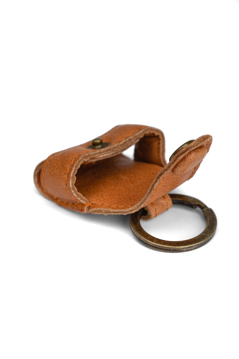 May include: A brown leather key chain with a small pocket and a brass ring.