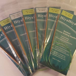 Peut inclure: Un ensemble de six aiguilles circulaires en bambou HiyaHiya de différentes tailles. Les aiguilles sont emballées dans des sachets en plastique transparent avec des étiquettes vertes et blanches. Les étiquettes indiquent la taille des aiguilles en mesures américaines et métriques, ainsi que le nom de la marque HiyaHiya.