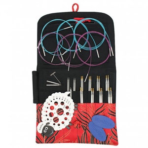 May include: A black zippered case with a red sheep design and a red zipper pull. The case contains a set of interchangeable circular knitting needles, a needle gauge, and two stitch markers.