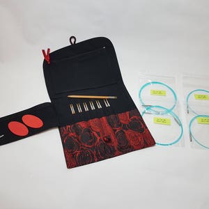 Puede incluir: Una funda de tela negra y roja con cierre de cremallera, que contiene un juego de agujas de tejer y un par de agujas circulares. Las agujas circulares est&aacute;n empaquetadas en bolsas de pl&aacute;stico transparentes.