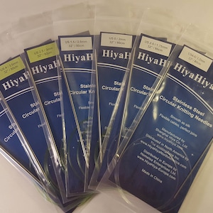 May include: A set of eight HiyaHiya stainless steel circular knitting needles in various sizes. The needles are packaged in clear plastic bags with blue and yellow labels. The labels include the size of the needles in US and mm, as well as the brand name HiyaHiya.