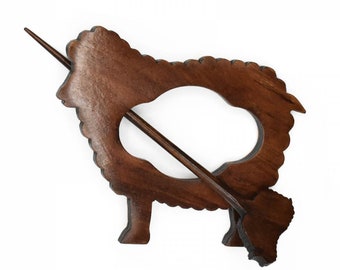May include: A wooden sheep-shaped shawl pin with a brown wooden stick. The pin is made of dark wood and has a detailed sheep design.