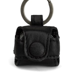 May include: A black leather keychain with a metal ring and a small flap closure. The keychain has a button on the front.