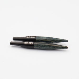 May include: Two knitting needles with black handles and dark green wooden shafts. The text "6.0 mm" is printed on the black handle of each needle. The needles are pointed at one end and are designed for knitting.