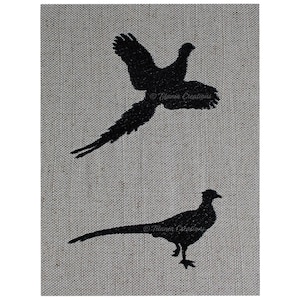 May include: Two black embroidered pheasant silhouettes on a beige linen fabric background. The top pheasant is flying with its wings spread. The bottom pheasant is standing with its head held high.