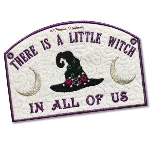 Puede incluir: Cartel bordado con el texto "THERE IS A LITTLE WITCH IN ALL OF US". El cartel presenta un sombrero de bruja negro con detalles florales, dos lunas crecientes y un borde morado. El fondo es blanco.