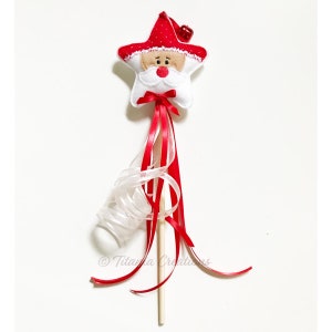 May include: A red and white felt star with a Santa Claus face and a red hat. The star is attached to a wooden stick with red and white ribbon streamers.