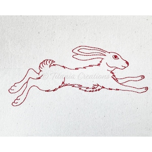 May include: A red embroidered design of a running rabbit on a white fabric background.