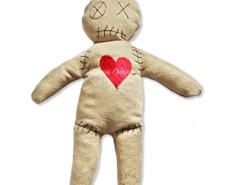 May include: A beige voodoo doll with black stitching and a red heart on its chest. The doll has a stitched-on mouth and X's for eyes.