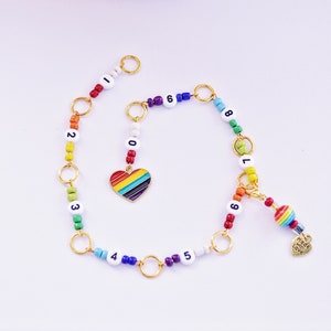 May include: Rainbow beaded bracelet with gold charms and a rainbow heart charm. The beads are numbered 0-9. The charm says "Made with Love".