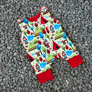 May include: A red and white sleeveless baby onesie with a colorful print of camping and woodland creatures. The onesie has a red trim around the neck and leg openings.