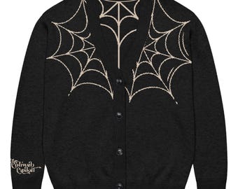 May include: A black long-sleeve button-up cardigan featuring a beige spiderweb pattern across the chest and neckline. The right sleeve cuff displays the text "Cobweb Casket" in a beige gothic-style font. The garment has a V-neckline.