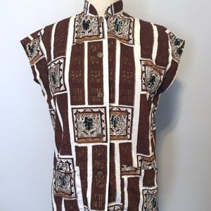 May include: A sleeveless button-down shirt featuring a brown and white geometric pattern with rectangular panels containing black Chinese characters and intricate decorative motifs. The shirt has a high collar, a front button placket, and two pockets.