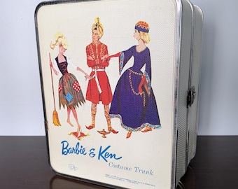 May include: A vintage off-white Barbie & Ken Costume Trunk storage case with a textured surface. The front features a colorful illustration of three figures in costumes, including a broom, a lamp, and the text Barbie & Ken Costume Trunk.